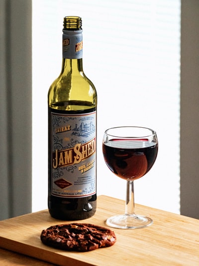 果酱棚旁边的酒瓶酒葡萄酒杯在木质表面

